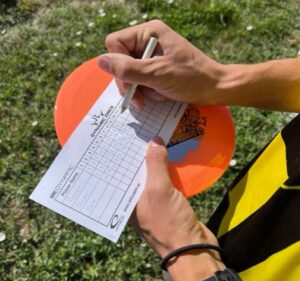 IMG 4103 e1661187288797 When it comes to disc golf scoring, there are a lot of similarities between Golf and Disc Golf. Some terms are the same, while other terms are different. Here are a few terms of which you should be aware of; par, birdie, eagle, ace, hazard, out of bounds, and penalty stroke. This link will take you to the PDGA's official rules for keeping score in a PDGA sanctioned tournament, and most non-PDGA sanctioned tournament play as well. That link refers to a scoring rule that is new for 2024. The new rule indicates that every player must keep score for the entire group. The rule allows a player's caddy to keep score for them. It is helpful for each player to understand the terminology associated with disc golf scoring.